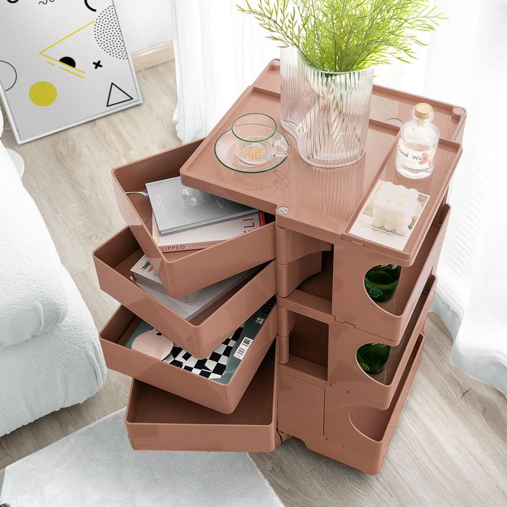5 Tier Bedside Table Organizer Pink with rotating trays, holding books, decor, and small items in a modern bedroom setting