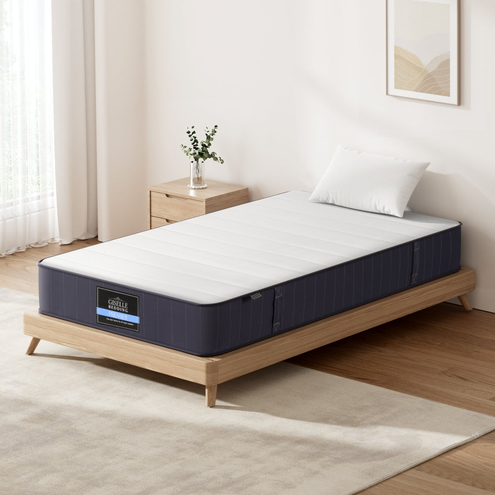 20cm Mattress King Single Bed Pocket Spring Mattresses with white top and navy sides on wooden bed frame in bright bedroom
