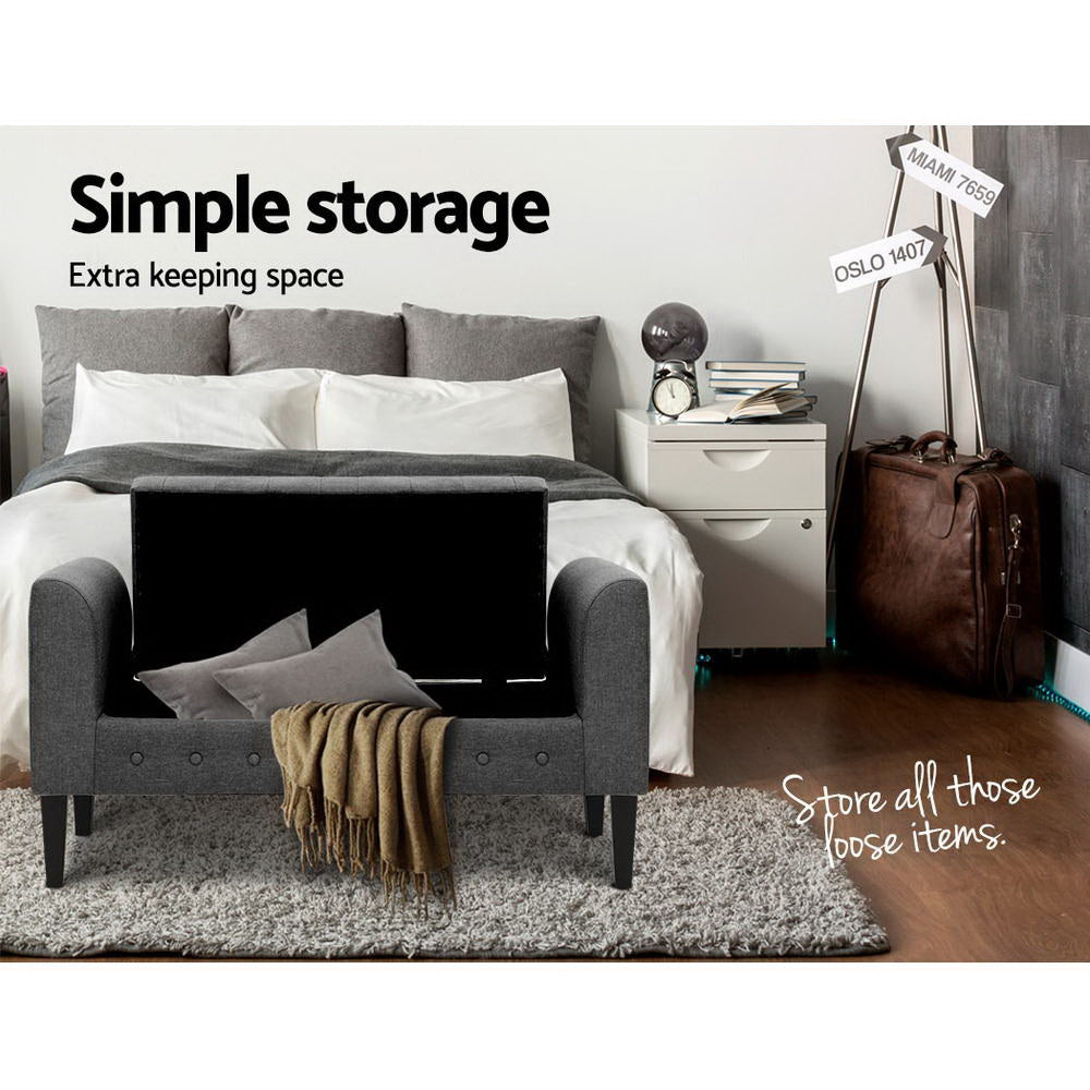 Fabric Storage Ottoman - Grey with lifted lid showing storage space, placed in bedroom with bed and nightstand
