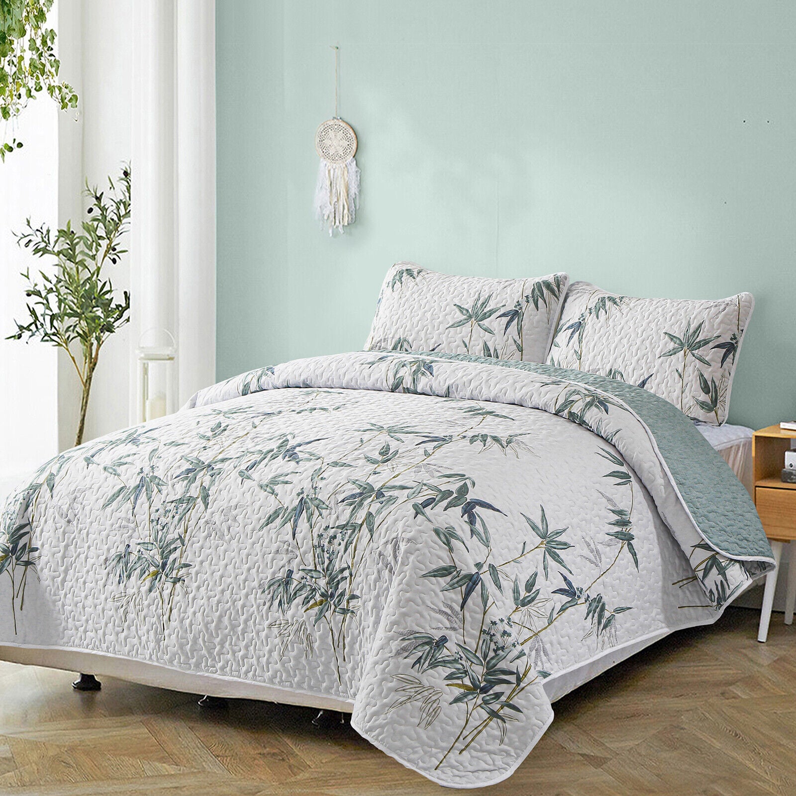 Soft leafey bloom Quilted 3 Pc Bedspread & Pillow Cover Set on a bed in a serene bedroom setting with light green walls.