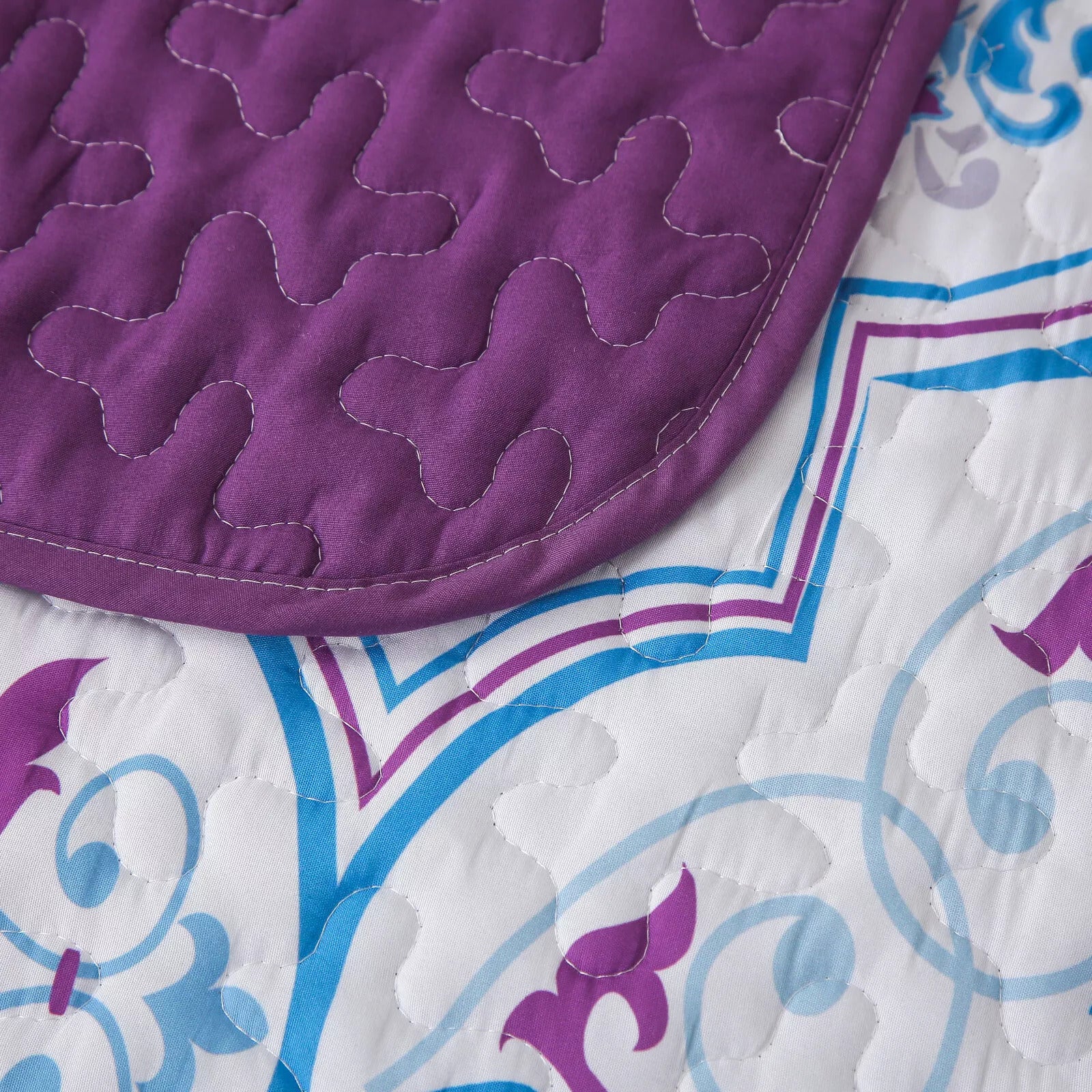Close-up of Handsome Quilted Bedspread and Pillowcases Set: Strong, Sturdy, and Stylish - Queen size with purple and blue pattern stitching.