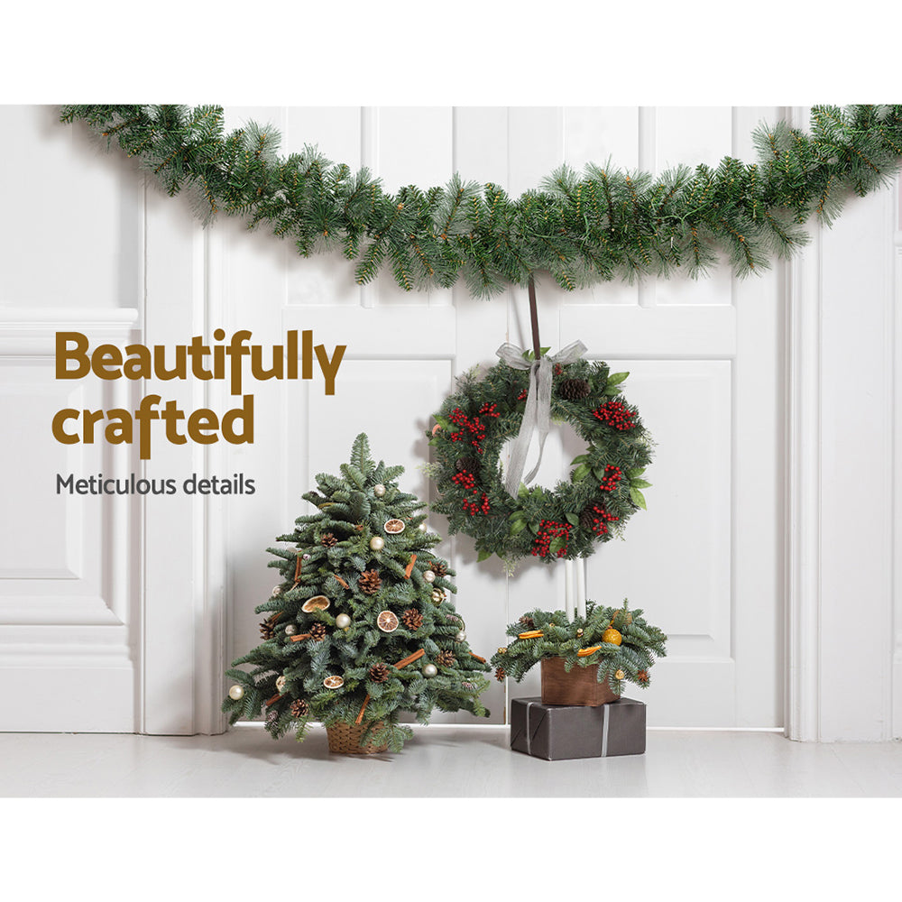 1.8m Christmas Garland with LED lights Party Xmas Decorations draped over white wall with matching wreath and small trees