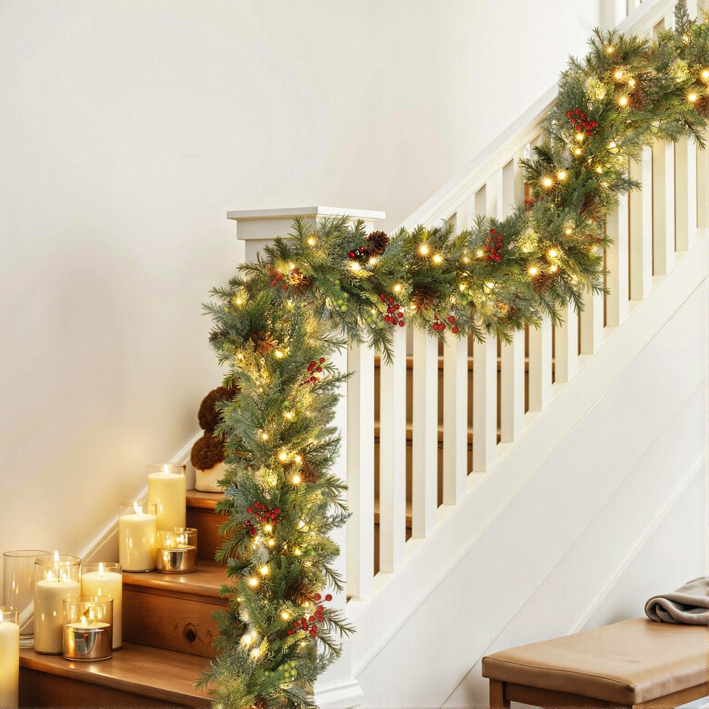 3M Christmas Garland Pre-lit LED with Pine Cones Xmas Decor Green draped along white staircase railing with warm lights and candles