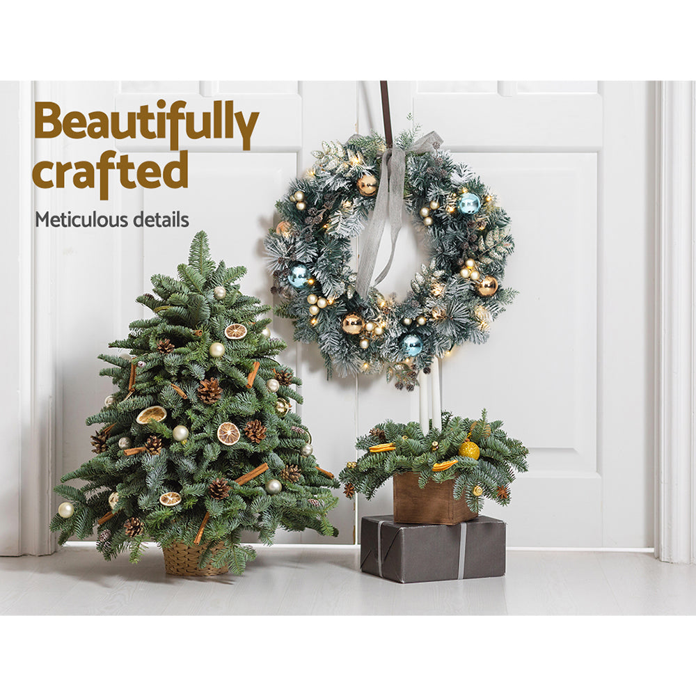 60cm Christmas Wreath with LED Lights Snowy Garland Xmas Decor hanging on white door with two festive green arrangements beneath