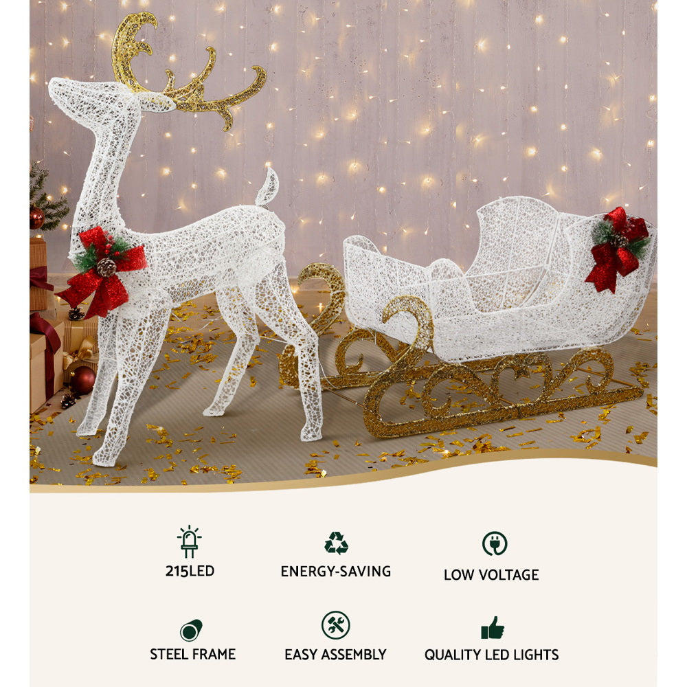 215 LED Christmas Lights Reindeer Sleigh Decorations with gold accents and red bows, glowing warmly against light backdrop