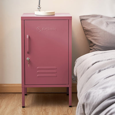 Bedside Table Metal Cabinet - MINI Pink with lockable door, metal construction, standing next to bed with gray bedding on wooden floor