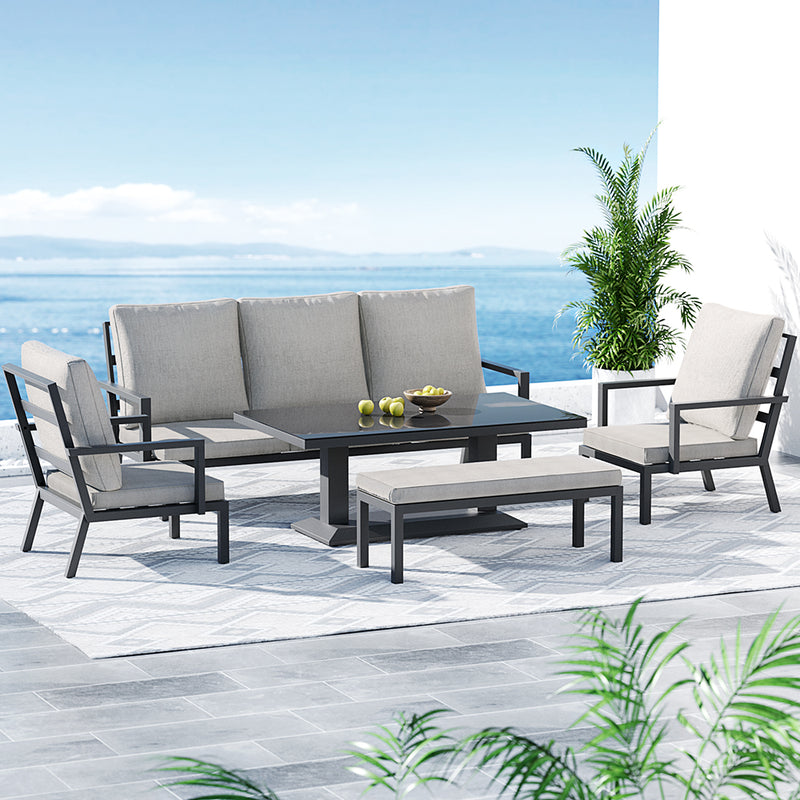 Torquay Outdoor Aluminium 7 Seater Lounge Set - Grey with cushions, table, bench, and armchairs on patio by the sea
