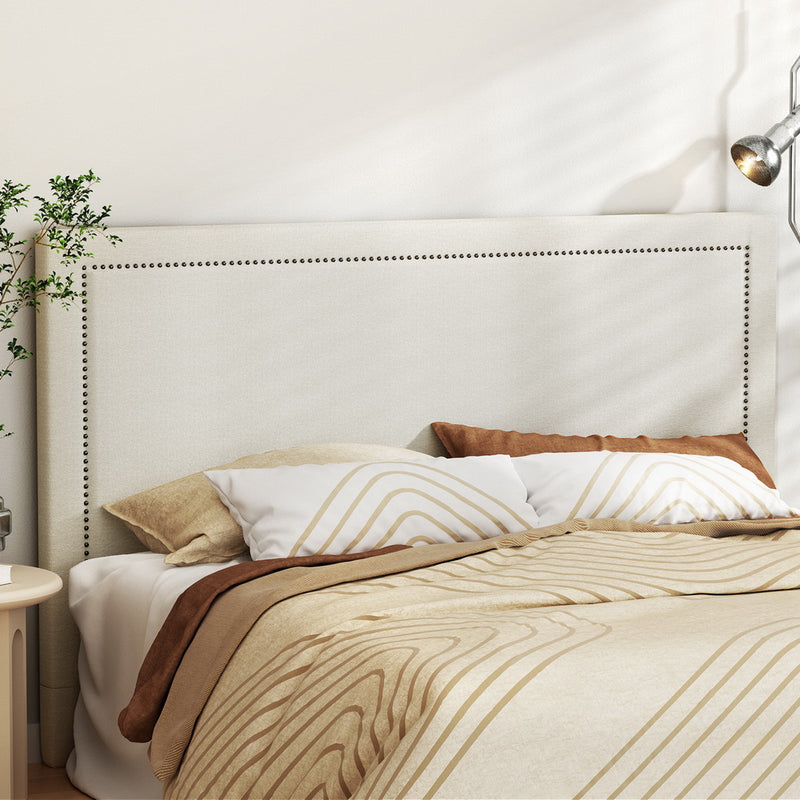 Rive King Size Headboard - Beige with nailhead trim, dressed bed with neutral linens in a modern bedroom setting