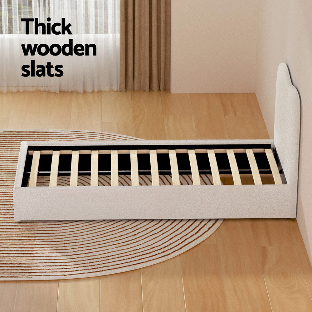 Albany Single Boucle Bed Frame - Cream White with thick wooden slats and upholstered frame on wooden floor with rug.