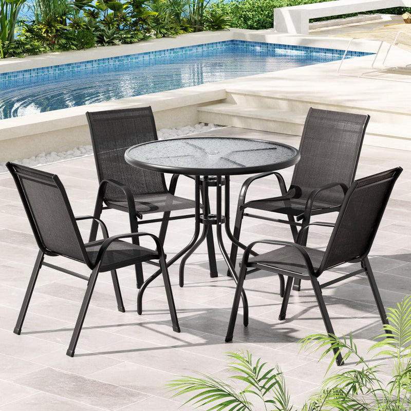 5-Piece Outdoor Dining Set with Table & Stackable Chairs - Black, featuring round glass table and mesh chairs by poolside