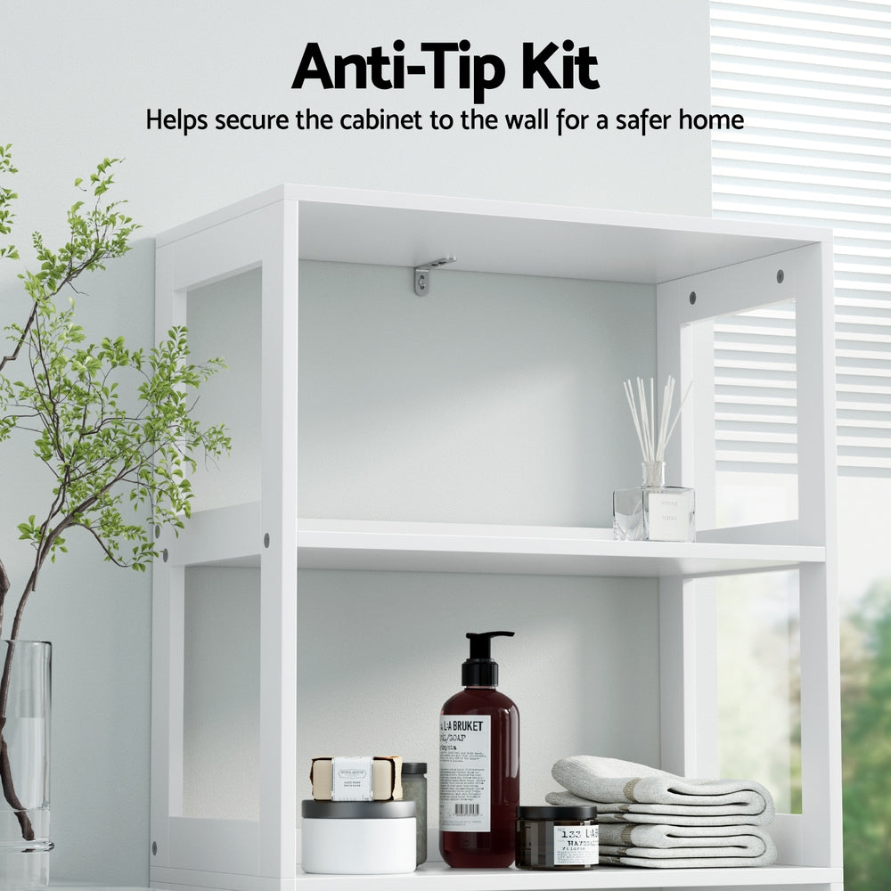 Bathroom Floor Storage Cabinet with 2 Drawers 3 Open Shelves 2 Doors White showing anti-tip kit securing cabinet to wall with bathroom items on shelves