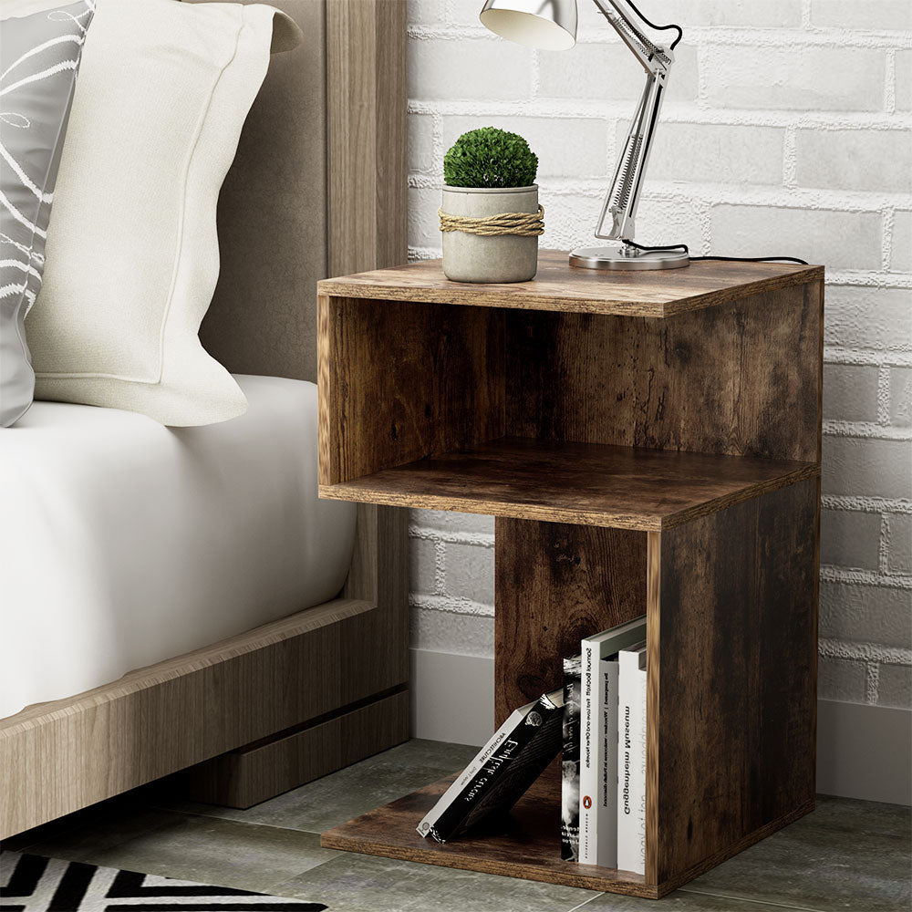Artistic Bedside Table - Rust Oak with open shelving, styled with books, small plant, and silver desk lamp in bedroom setting