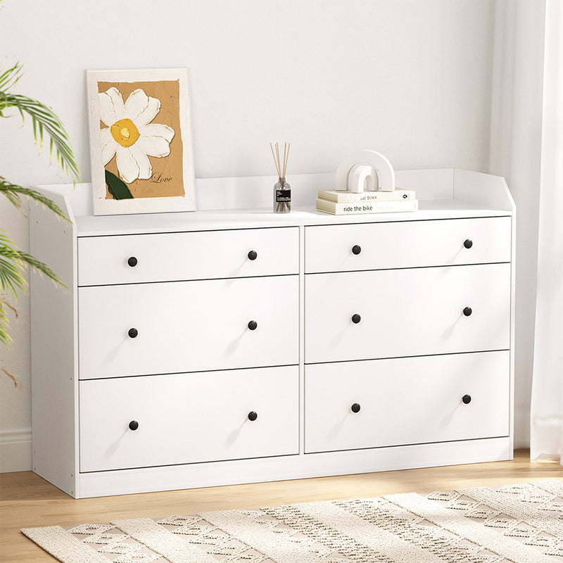 6 Chest of Drawers - PETE White with six black knob drawers and decorative items on top in a bright bedroom setting