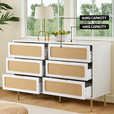 Byron 6-Drawer Rattan Tallboy – White & Pine with six open drawers, rattan fronts, gold legs, and a lamp on top in a bedroom setting