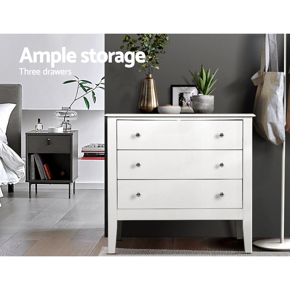 Chest of 3 Drawers Storage Cabinet White with sleek knobs, standing on tapered legs in a modern bedroom setting