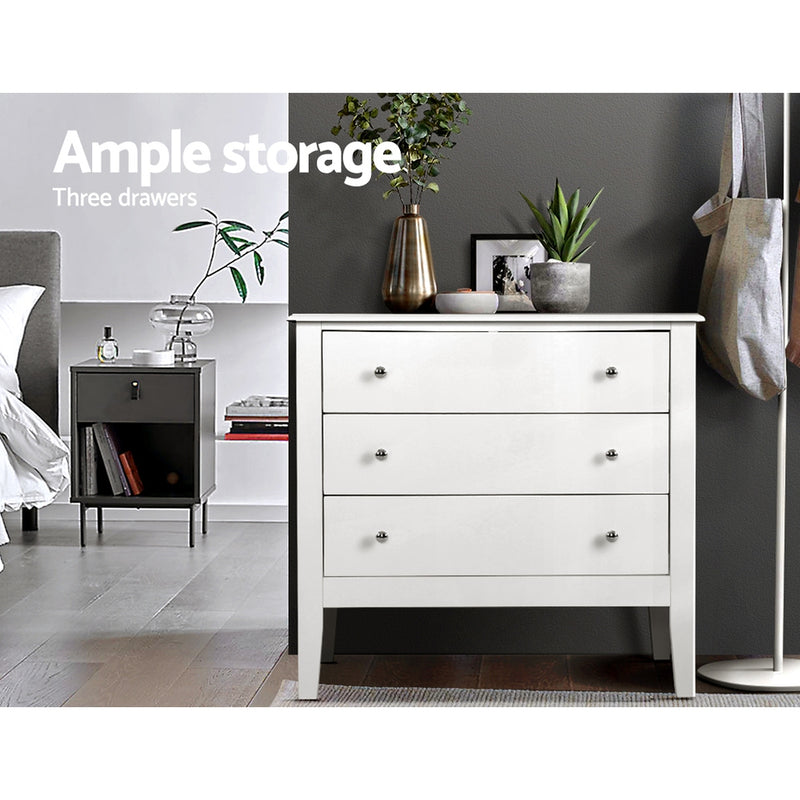Chest of 3 Drawers Storage Cabinet White with sleek knobs, standing on tapered legs in a modern bedroom setting