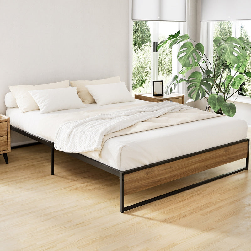 Oslo Metal Queen Bed Frame with black metal and wood accents in bright bedroom setting with plants and side tables
