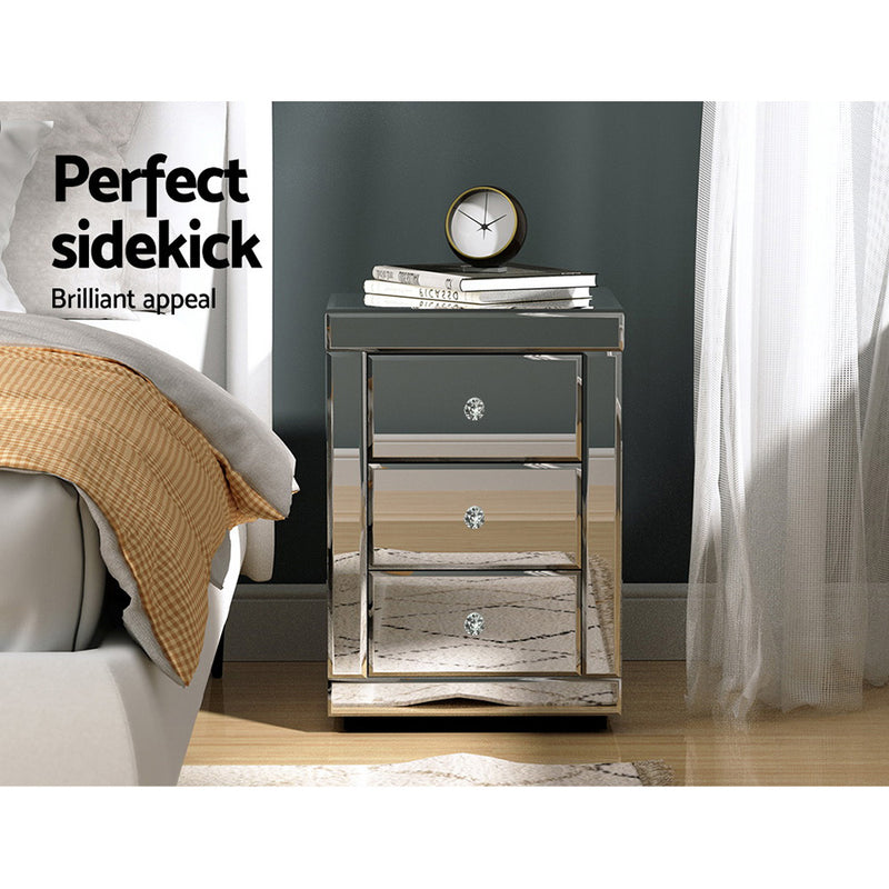 Mirrored Bedside Table Drawers Furniture Mirror Glass Presia Silver with three drawer handles and decorative items on top in bedroom setting