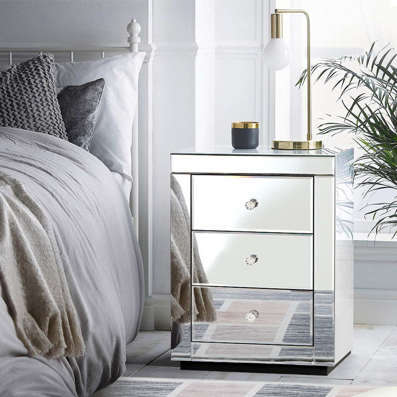 Mirrored Bedside Table Drawers Furniture Mirror Glass Presia Silver with three drawers, crystal knobs, and modern decor on top.