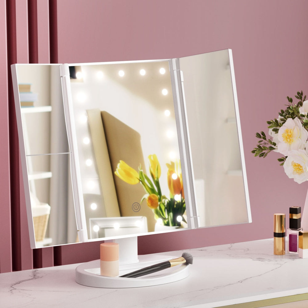 Tri-fold Makeup Mirror 1X2X3X Magnifying with LED Light Travel Portable on white base with makeup and flowers nearby