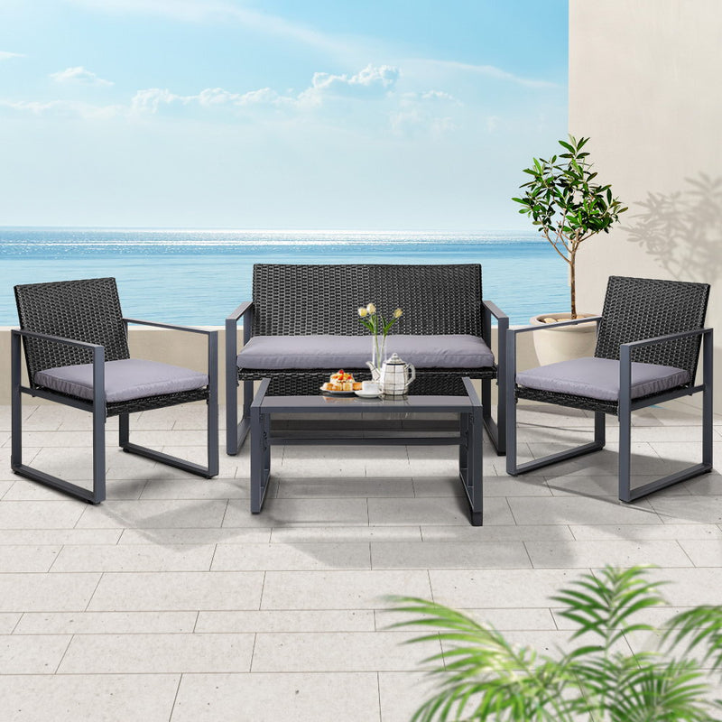 4 PCS Outdoor Sofa Set Rattan Furniture Glass Top Table Chairs Black with gray cushions on terrace by the sea