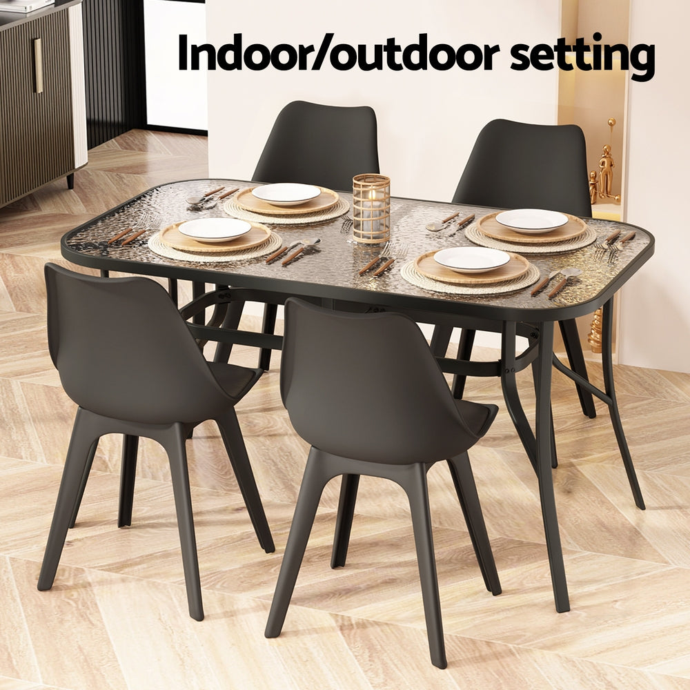 140cm Outdoor Dining Table With Glass Top and Parasol Hole – Black with four black chairs in indoor setting