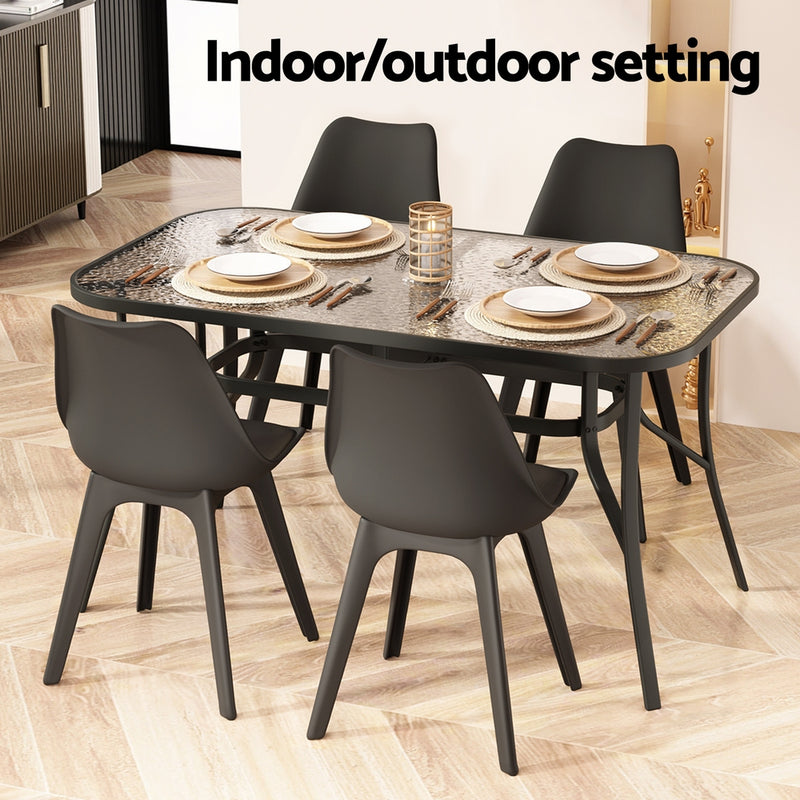 140cm Outdoor Dining Table With Glass Top and Parasol Hole – Black with four black chairs in indoor setting