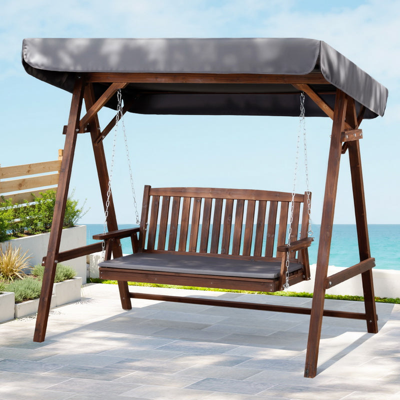 Wooden Swing Chair Garden Bench Canopy 3 Seater Outdoor Furniture with cushioned seat and fabric canopy on patio by the sea