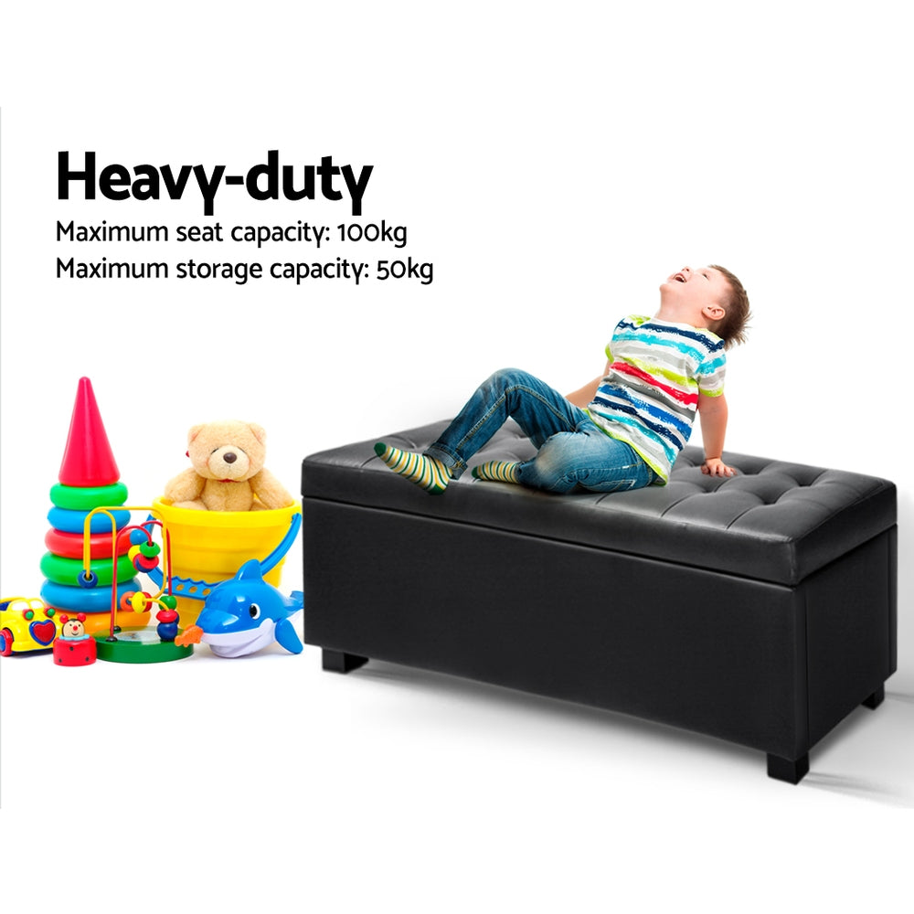 Black PU Leather Storage Ottoman - Black with tufted top, sturdy legs, shown with child sitting and colorful toys nearby