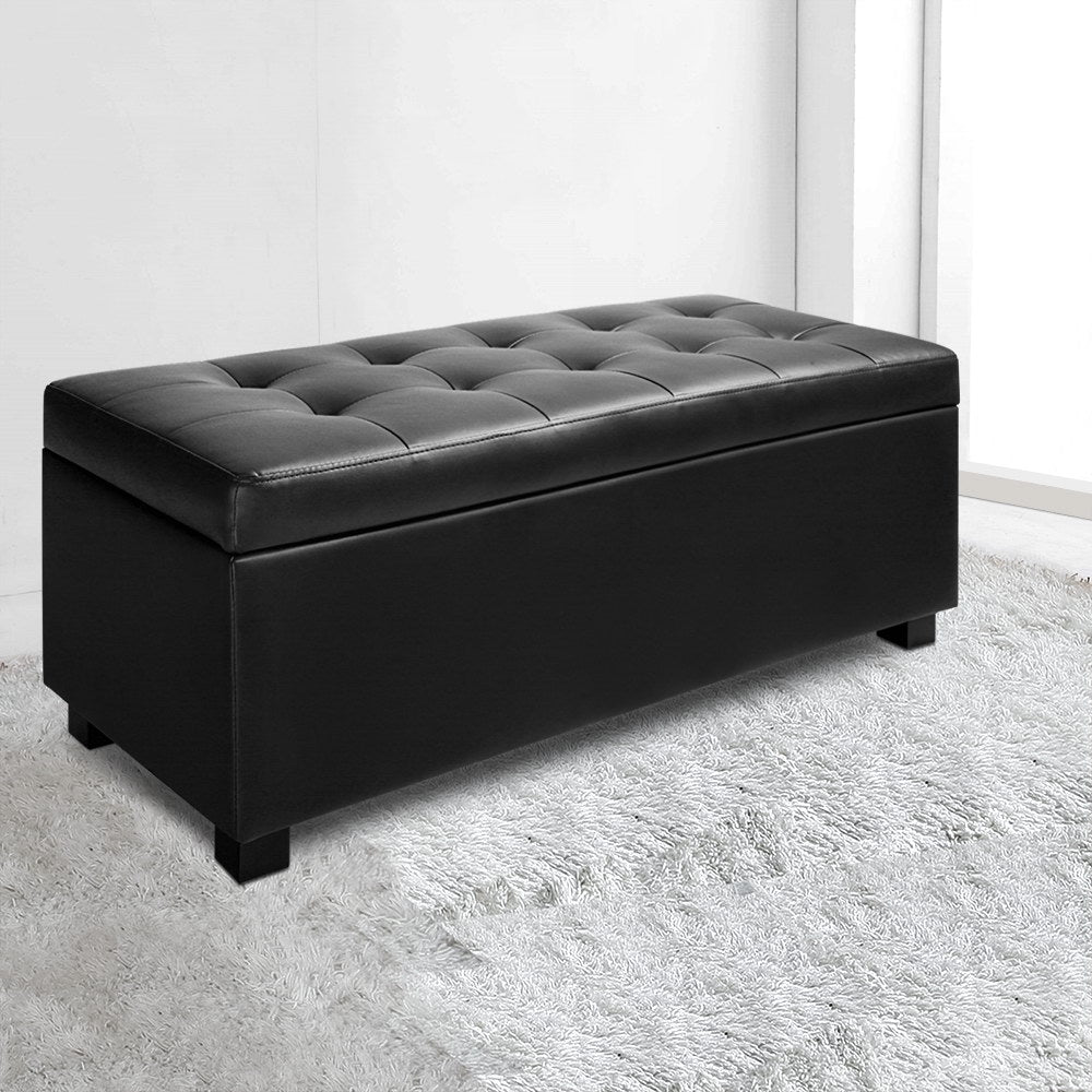 PU Leather Storage Ottoman - Black with tufted top and storage inside, set on black feet on a light rug background