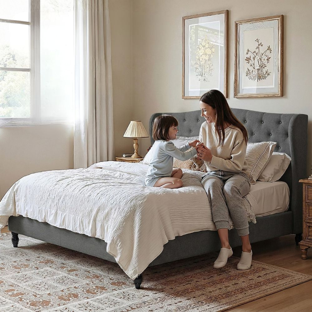 Pierre King Bed Frame with Wingback Headboard – Grey in a bedroom setting with woman and child on the bed