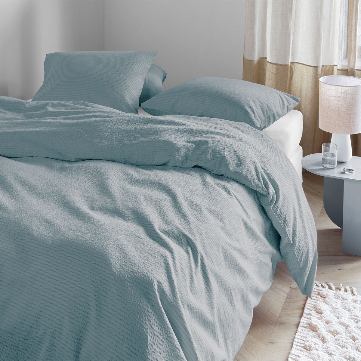 Bedding House Summer Blue Grey Seersucker Cotton Quilt Cover Set Queen on bed in bright bedroom with side table and lamp