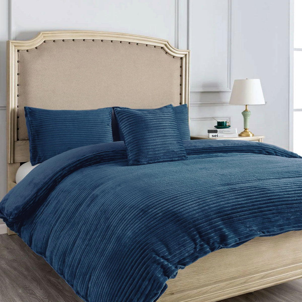 Ruby Navy Quilt Cover Set Double in plush navy fabric styled on beige upholstered bed with nightstand and lamp