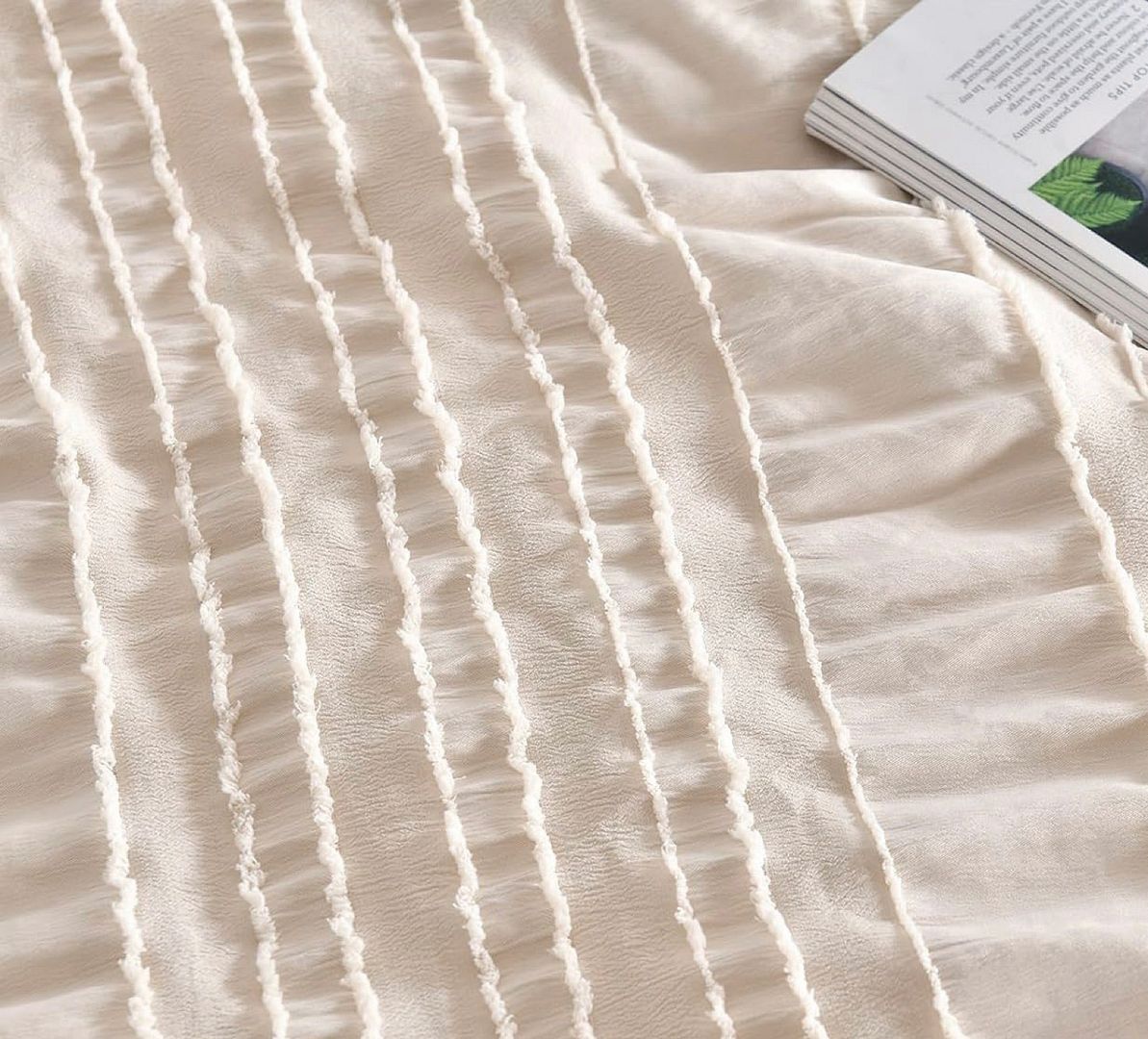 Close-up of textured cream fabric with tufted stripes and a book, part of the Tufted Boho Striped Embroidery Quilt/Doona/Duvet Cover Set - King Size