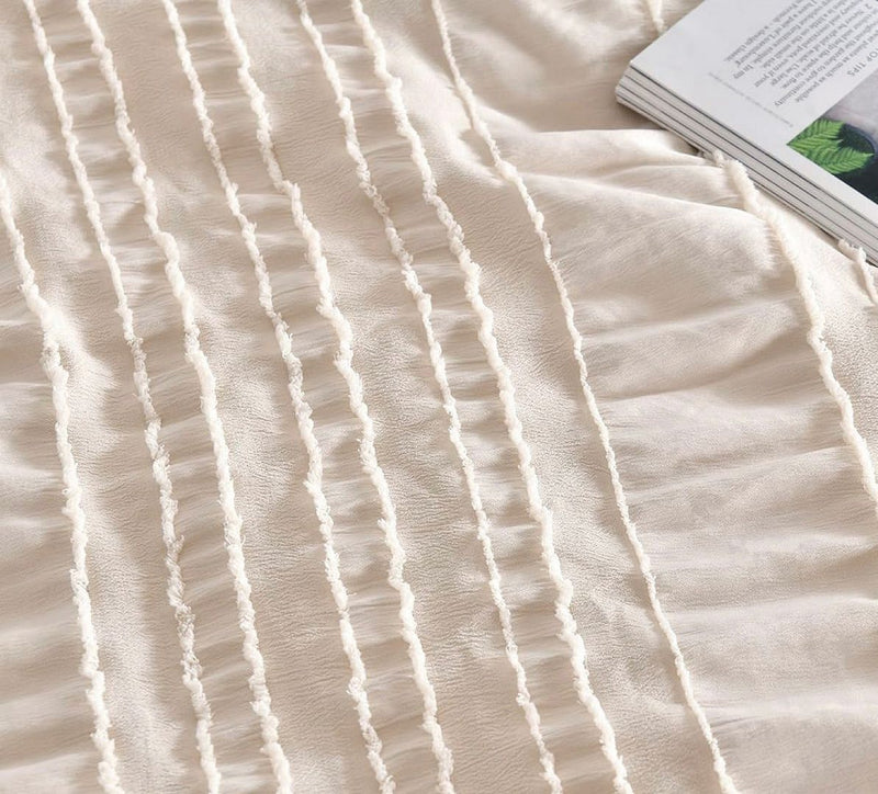 Close-up of textured cream fabric with tufted stripes and a book, part of the Tufted Boho Striped Embroidery Quilt/Doona/Duvet Cover Set - King Size