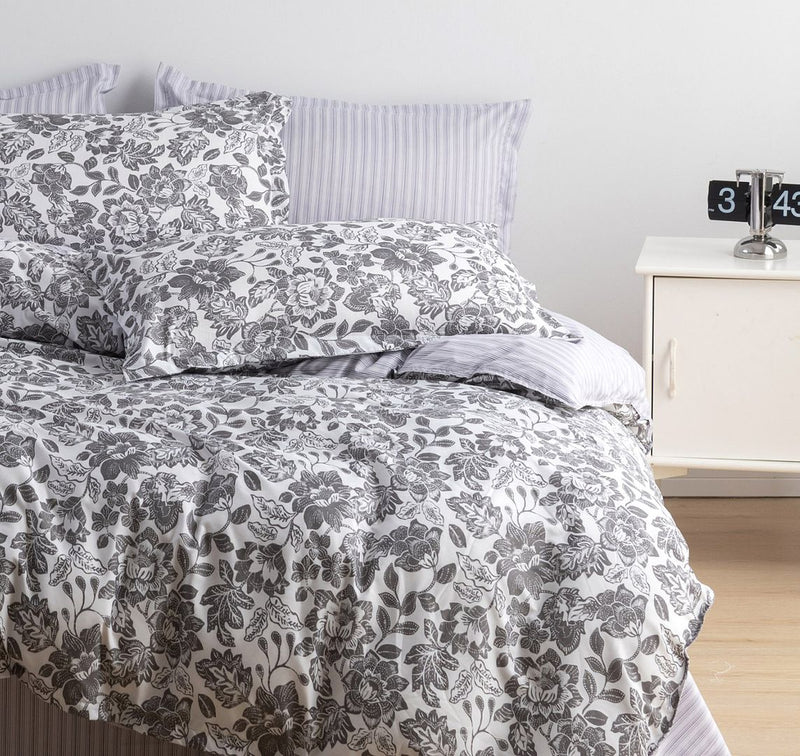 Matira Quilt Cover Set - Queen Size with black and white floral pattern and striped pillowcases on a styled bed with bedside table