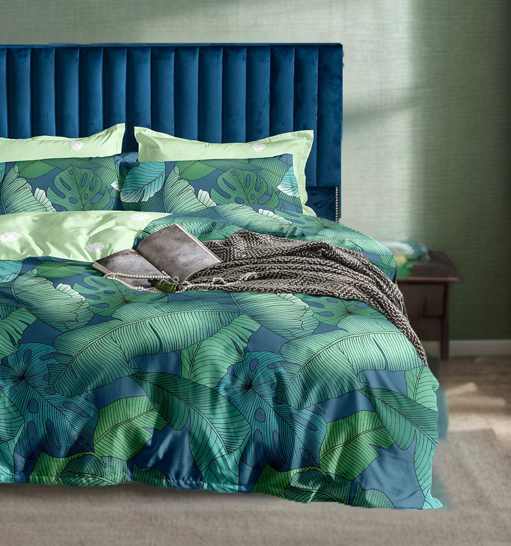 Kalena Leaves Quilt Cover Set - Queen Size on bed with tropical leaf print and blue velvet headboard in bedroom setting
