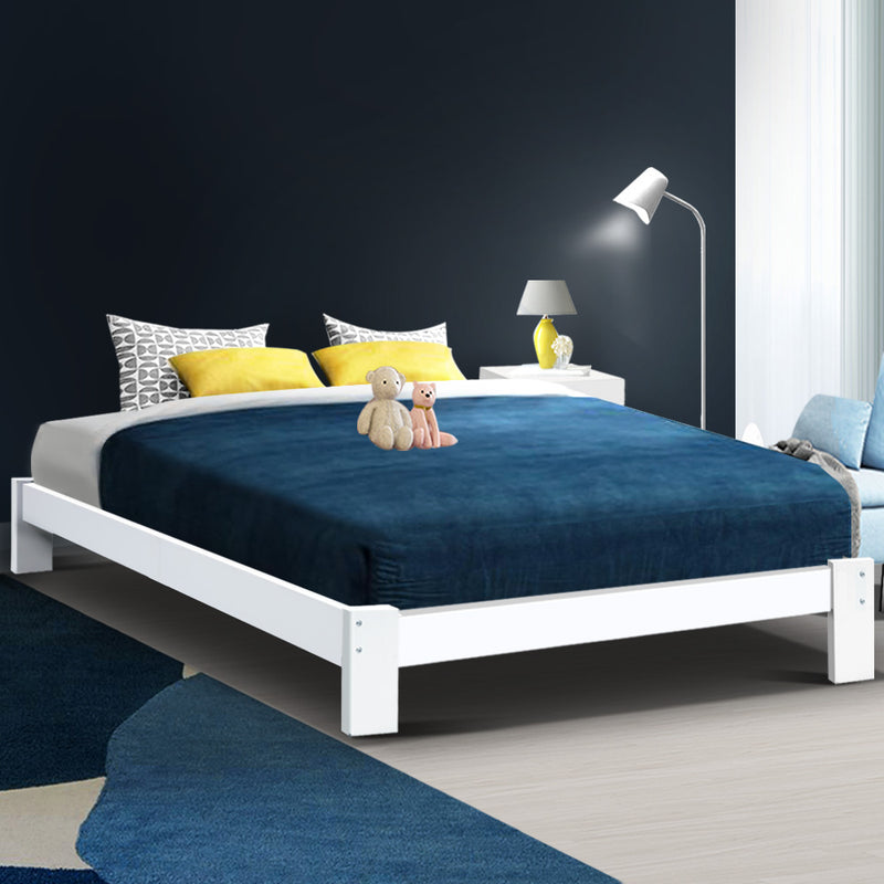 Fairy Wooden Queen Bed Frame White with solid pine wood, navy bedding, yellow pillows, and bedside lamp in modern bedroom setting