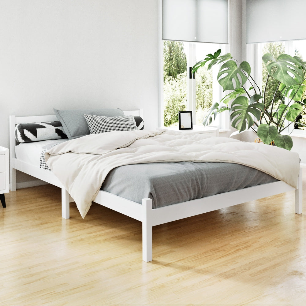 Whitehaven Wooden Double Bed Frame White in bright bedroom with wooden floor, patterned cushions, and indoor plants