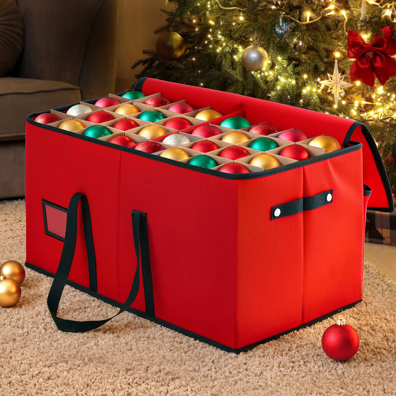 Christmas Baubles Storage Box 128 Slots Decor Ornaments Container in red fabric with black handles holding colorful baubles near decorated Christmas tree