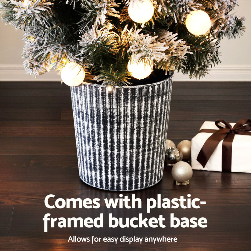Christmas Tree 1.2M Potted Snowy Xmas Tree with warm white LED lights in textured black plastic bucket base on wooden floor