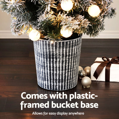Christmas Tree 1.2M Potted Snowy Xmas Tree with warm white LED lights in textured black plastic bucket base on wooden floor