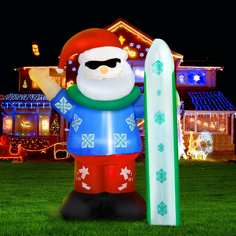 Christmas Inflatable Santa 1.6M Illuminated Decorations with sunglasses, blue sweater, red pants, and snowboard on lawn at night